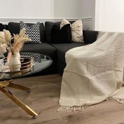 white walls and wood floor with black sofa and round glass and gold metal coffee table.