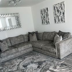 modern grey living room with abstract grey rug and artwork, grey velvet sofa and large wall furniturebox mirror with starburst frame