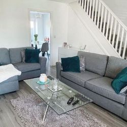 grey and white living wiim with dark forest green cushions and a rectangular glass and silver chrome coffee table