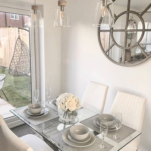 bright modern dining room with glass dining table and white roses