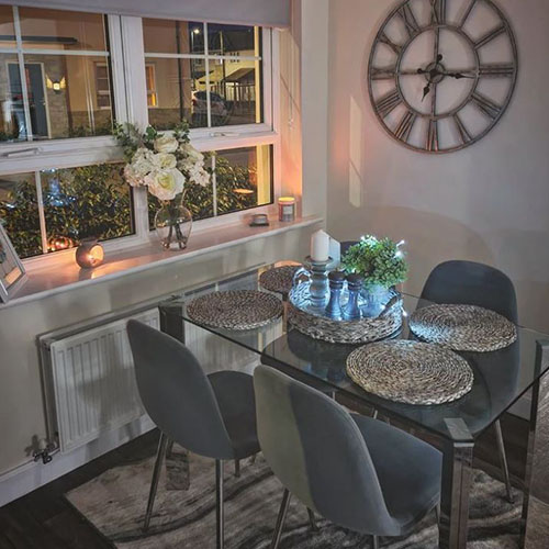 glass rectangular dining table wit white roses and candles with rattan tray and placemats