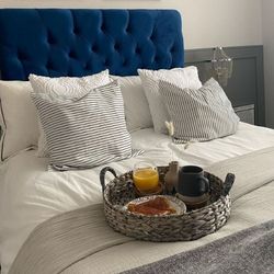 navy blue velvet upholstered bedframe with button tufted chesterfield design, and white linens