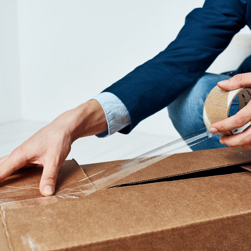 Image of a person packing sealing a packing box. declutter to prepare your home for sale