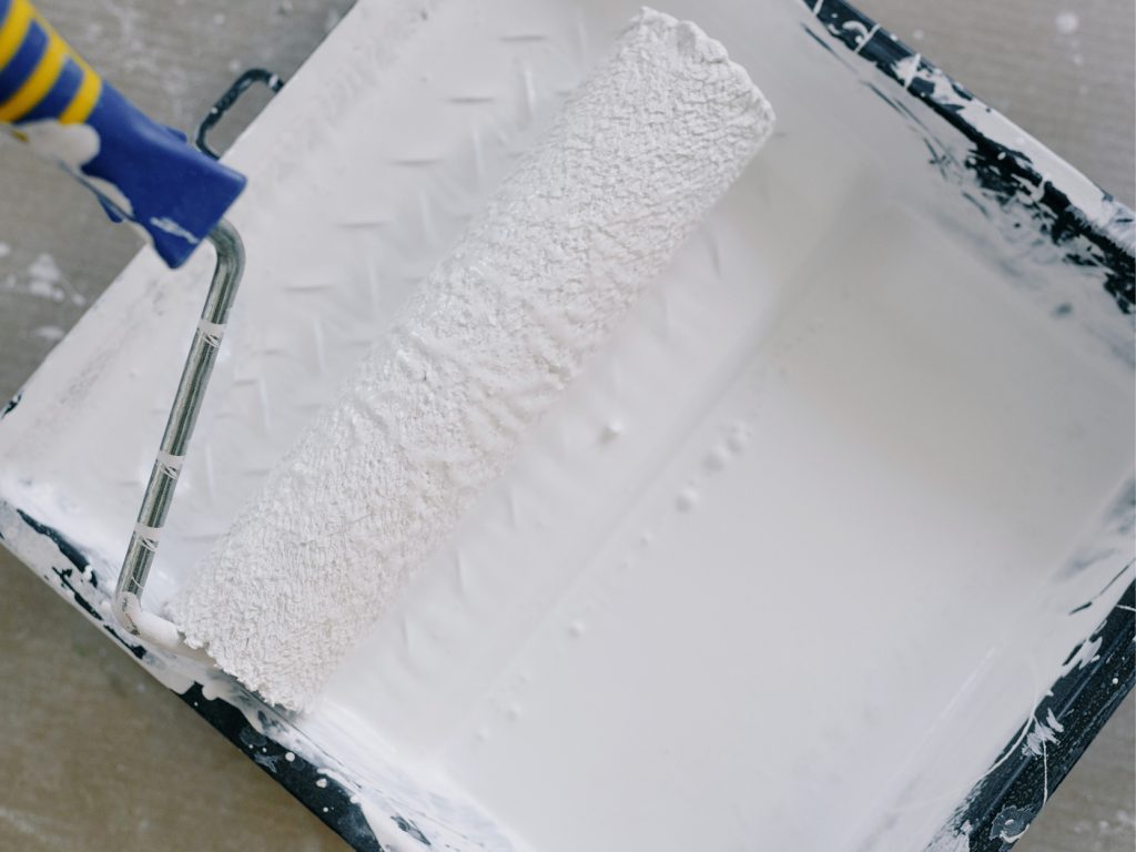 image of a paint roller tray containing white paint. Freshen up paintwork to prepare your home for sale