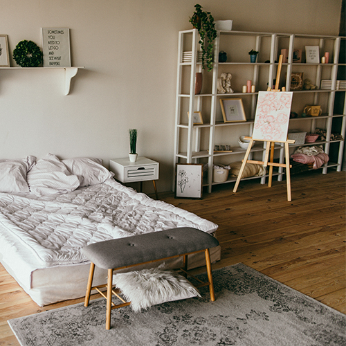 Photo of bedroom with vintage style rug placed at the foot of the bed. 