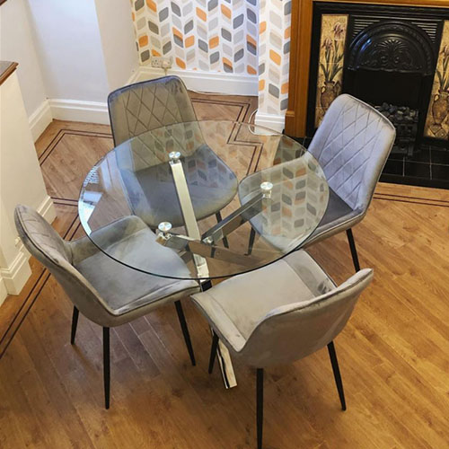 Round glass table with grey chairs in Scandinavian dining room setting, with chevron wall paper in yellows and greys.