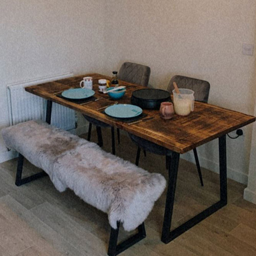 wooden table with 2 velvet chairs and a bench seat with faux fur throw on it creates a Scandinavian dining room look.