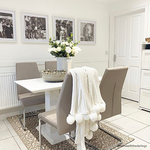 A cream and white dining area with a rug under the table