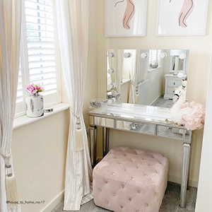 A silver dressing table in the corner of a cream and pink room