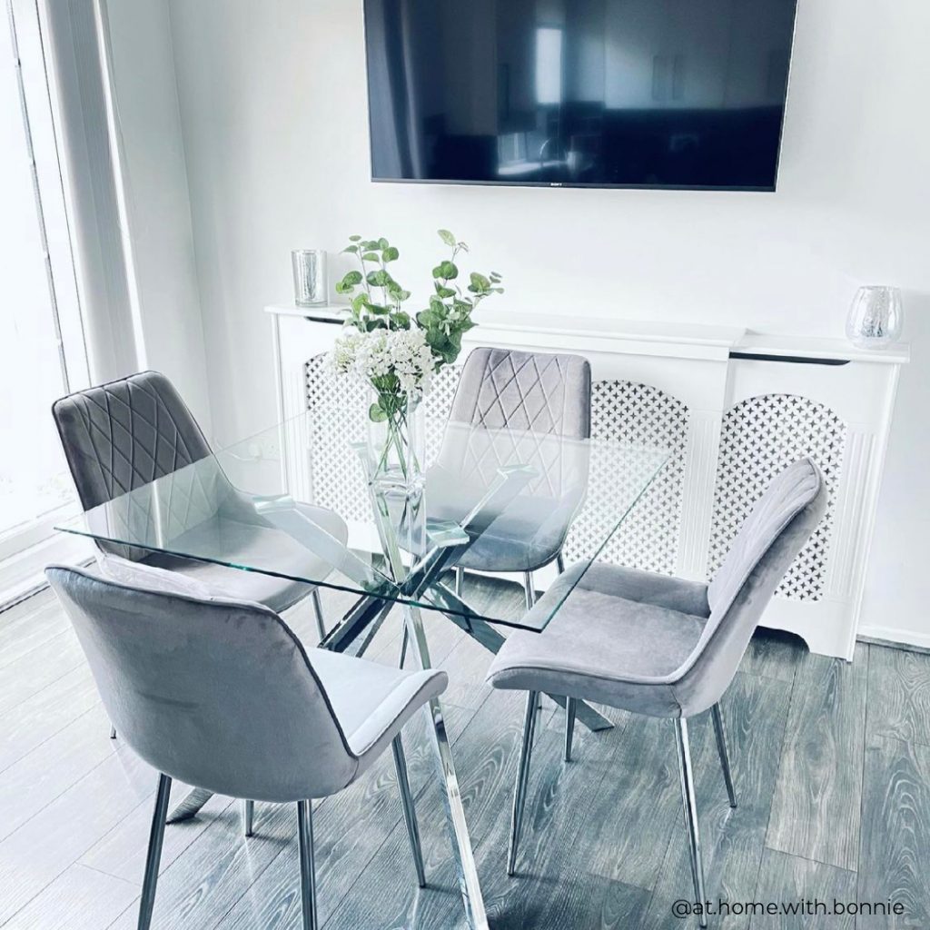 A cream and grey and glass dining set with a stylish and contemporary kitchen in the background