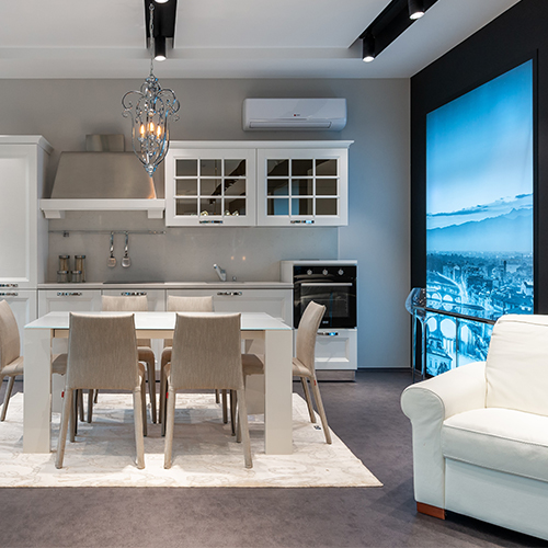 image shows a rug under a dining table within a larger open plan living area - a sofa and a kitchen area can also be seen. 