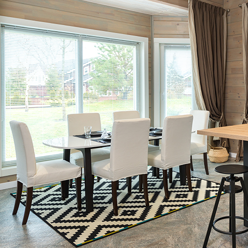 modern dining table and chair set - all white with black legs - sit on top a black and white patterned rug.