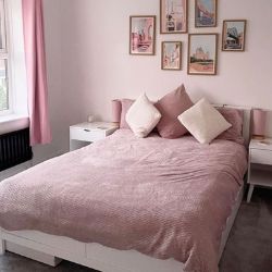 white pine bed with drawers underneath for storage, dressed in pink linens in pink room with white wooden bedside tables. Gallery wall above bed