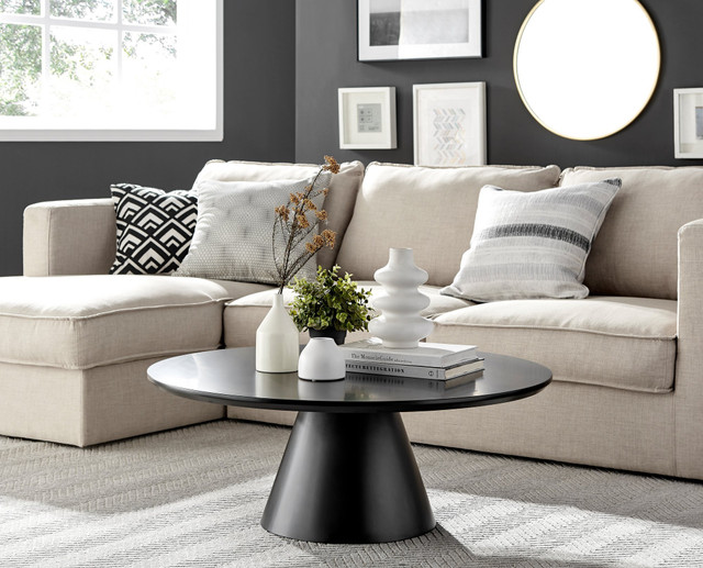 round black coffee table with central pedestal leg in beige and white living room.