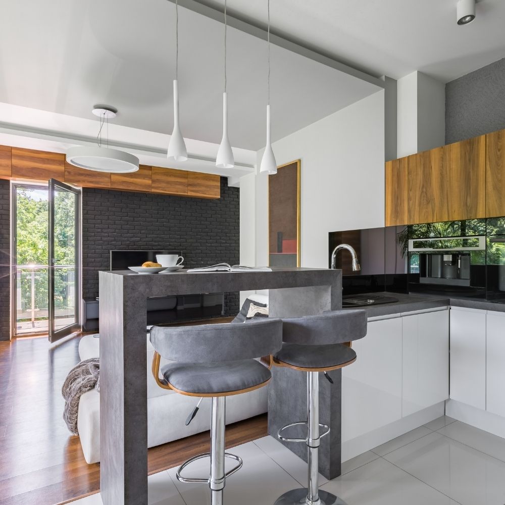 modern open plan kitchen diner featuring grey minimalist breakfast bar and 2 grey velvet bar stool chairs