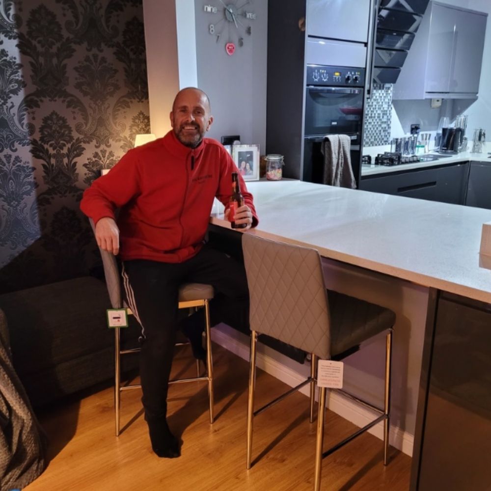 smiling man sat on grey faux leather bar chair stool