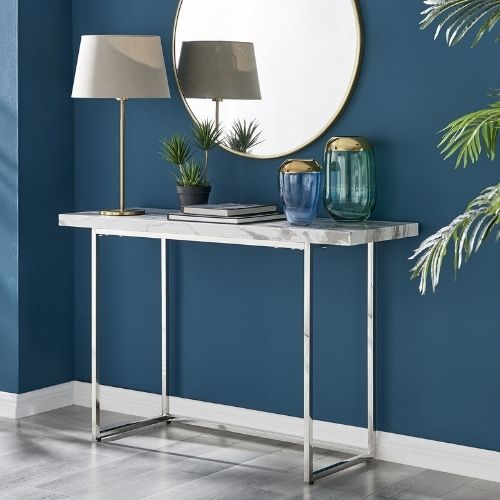marble effect console table with thin silver chrome legs beneath round gold framed wall mirror