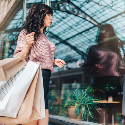 black friday shopper with armful of bags gazes through shop window