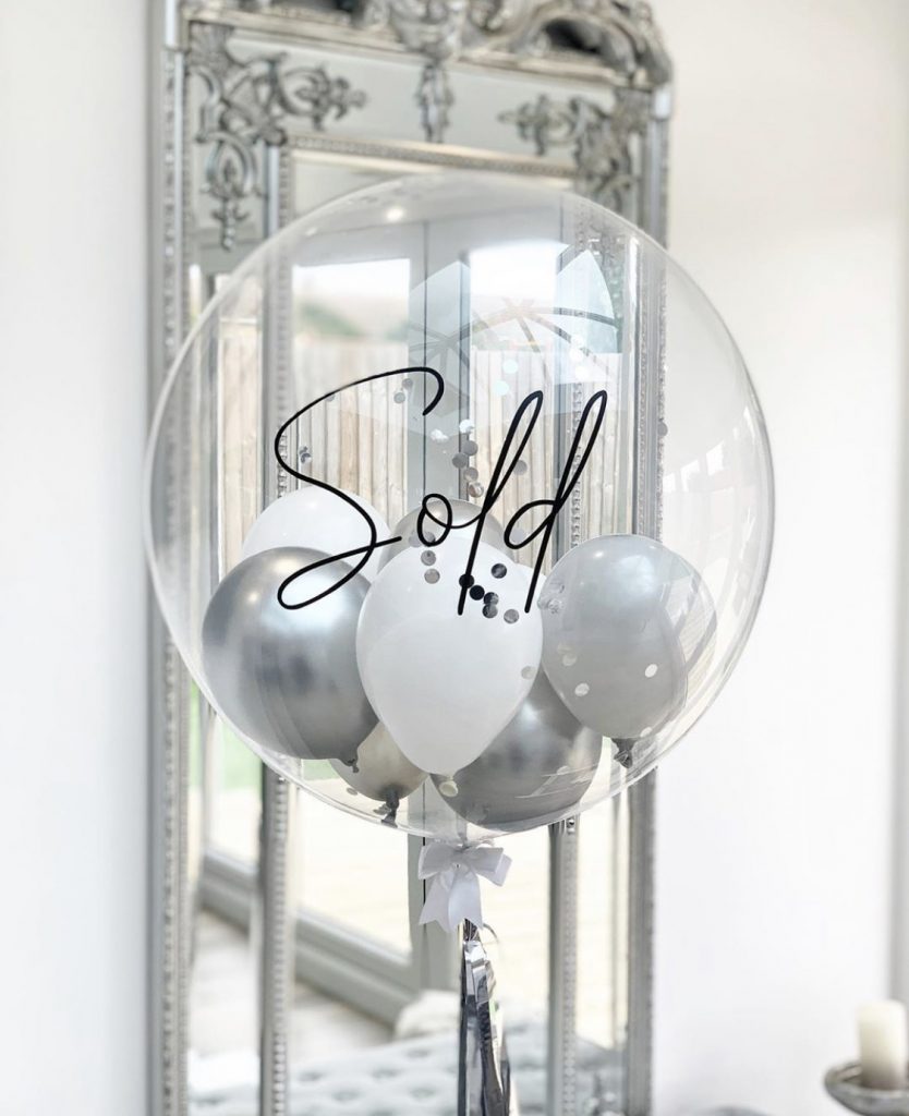 A grey and white balloon with sold written on it