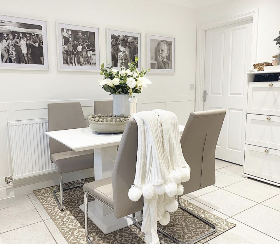 A white and cream dining space with family photos on the walls