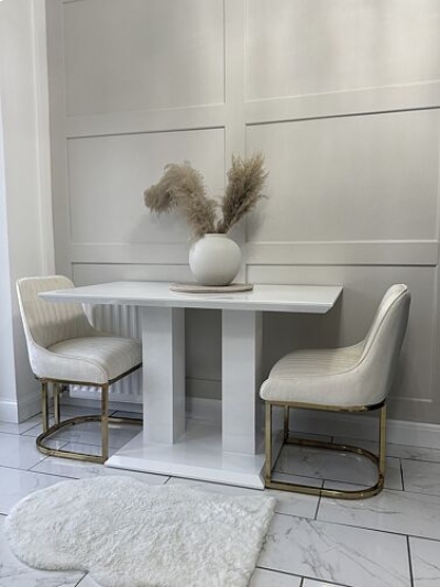 ancient Greece inspired dining space with white high gloss table on two column plinth legs, and two white fabric and gold dining chairs in stylish dining room