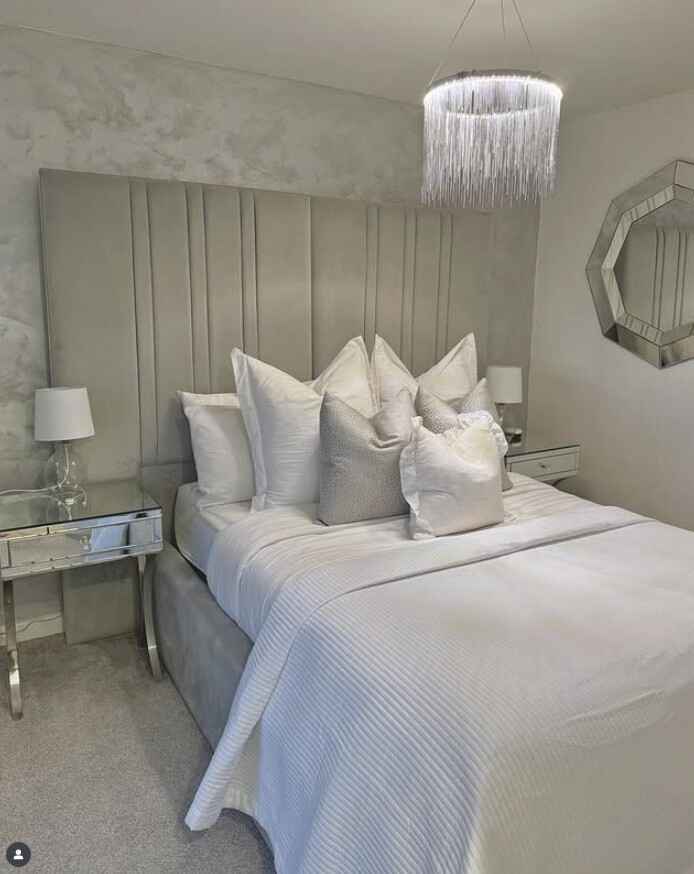 stylish modern grey bedroom with grey velvet bed headboard, mirrored bedside tables and modern chandelier light