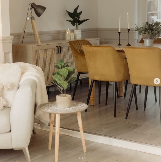 modern warm neutrals living room and dining room space - dining room has wooden table & yellow velvet dining chairs, living room has white boucle armchair.