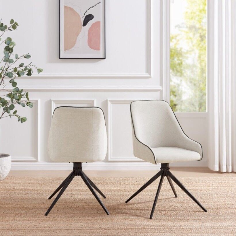 cream fabric swivel chair with black piping, on black metal legs, in bright modern living room space