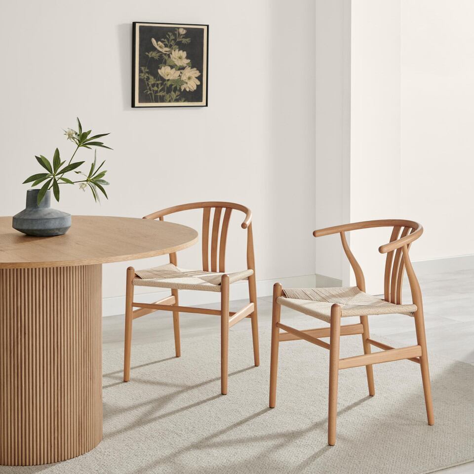 oak stain wood dining chairs in wishbone style in bright dinign room beside round fluted wood pedestal dining table