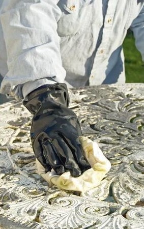 hand in black glove wiping metal garden table