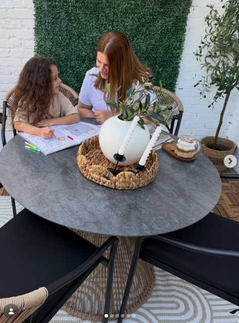 a mother and aughter sat at a round marble dining table