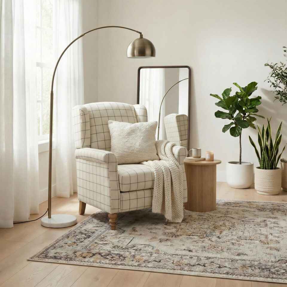 wingback rmchair in cream check gingham fabric on floral rug with mirror and standing lamp behind in bright modern cottagecore living room space