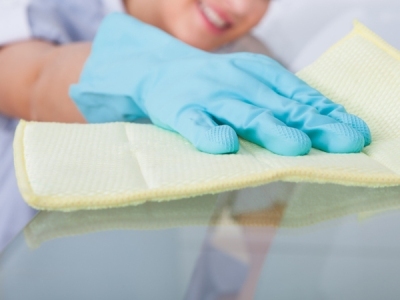 person in blue gloves cleaning a glass dining table