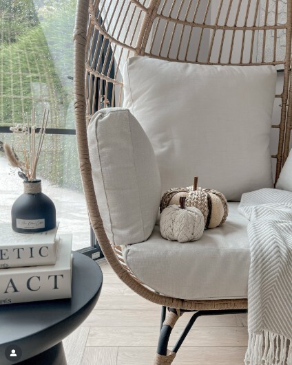 rattan egg chair indoors styled with plush fabric pumpkins