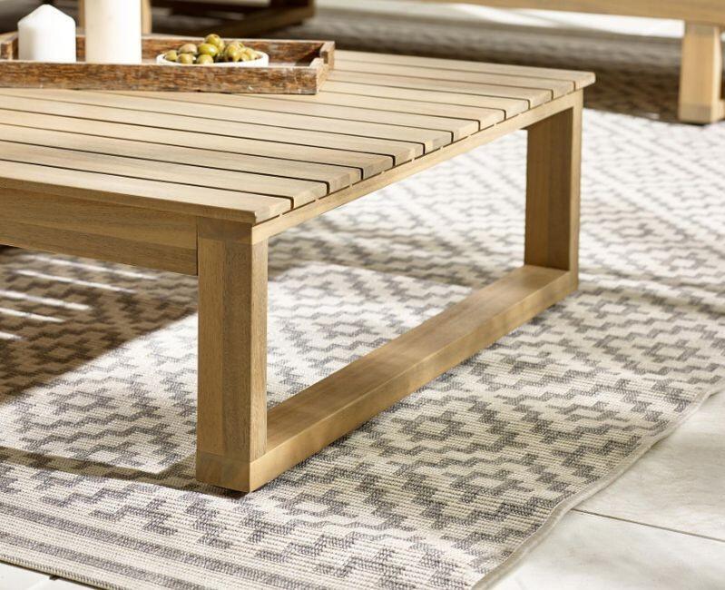 close up of wood garden coffee table and bench on outdoor rug, elevated on rubber feet