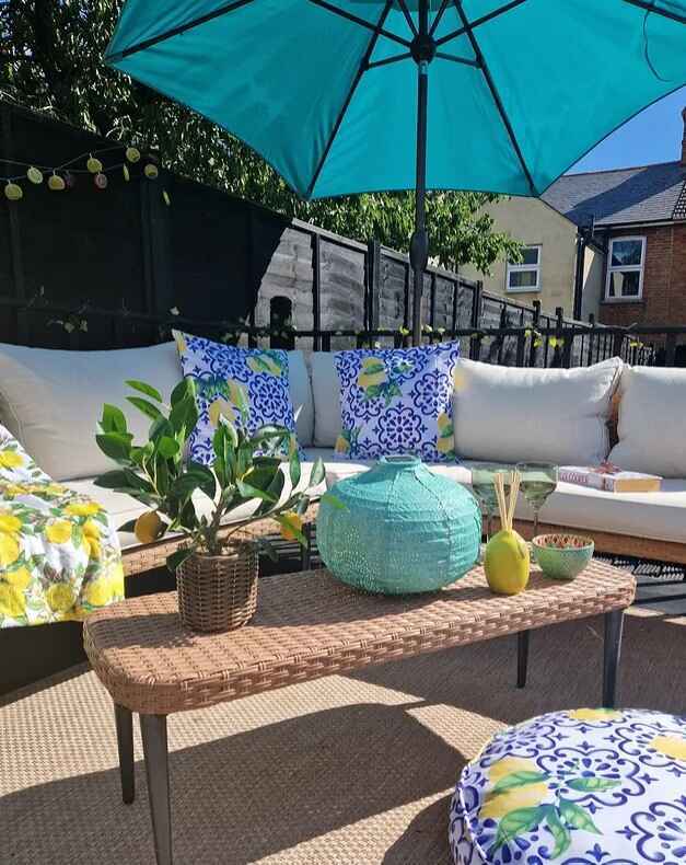 beige rattan garden corner sofa set with colourful citrus fruit decor and turquoise parasol