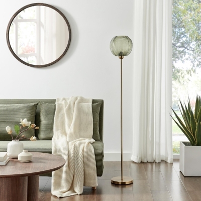 green glass globe standing floor lamp beside green sofa and round coffee table in Mid Century Modern style living room