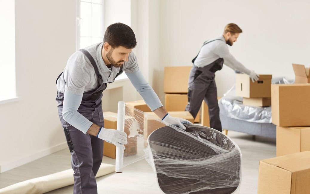 2 professional home movers in overalls moving furniture safely