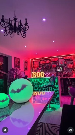 white high gloss dining table decorated for Halloween in bold and bright dining area, with orange purple and green lighting