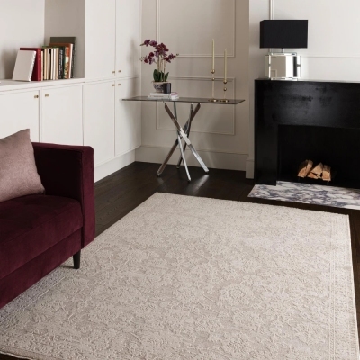 neutral rug with pale floral lace pattern in bold living room with maroon sofa, black marble side table and fireplace