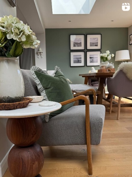 modern green living room with mid century modern wood & green fabric chair, wood & marble round side table, and flowers in vase