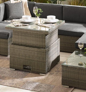 grey rattan rising garden coffee to dining table with coffee cups and wine glass on it, with grey modular rattan sofa behind it