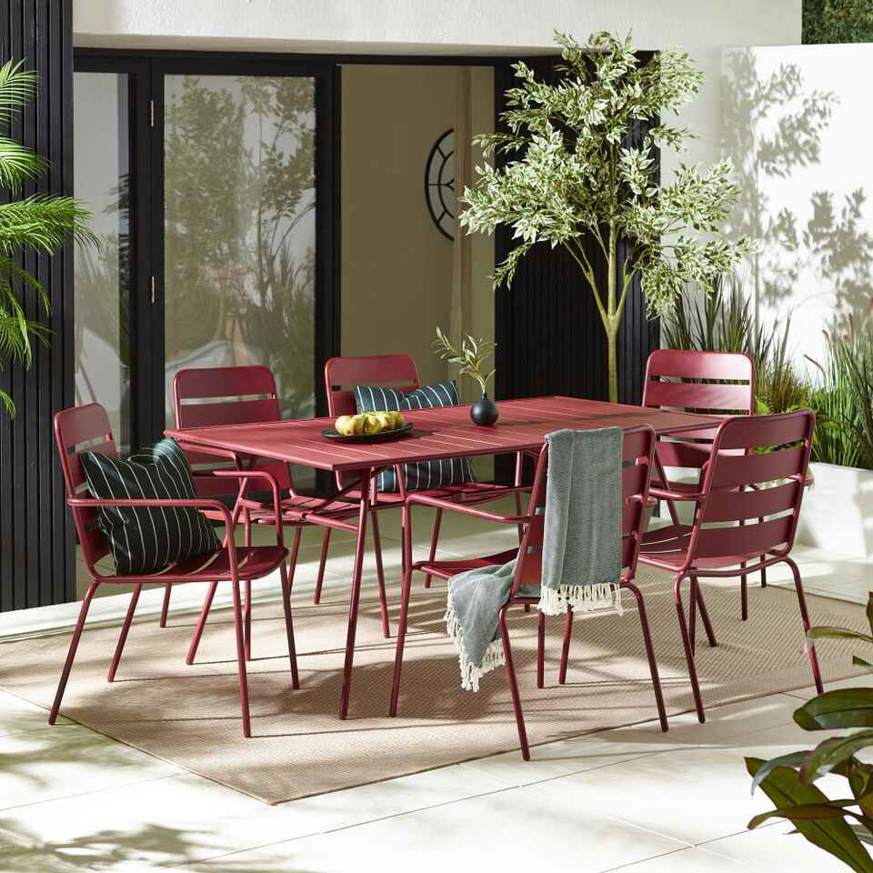 red metal garden dining set on paved patio with open french door windows and modern home behind