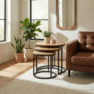 3 round wooden nesting coffee tables with black round metal legs in modern bright and warm living room beside tan leather sofa