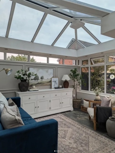 patterned rug used for room zoning in a living space inside a conservatory, with blue velvet sofa