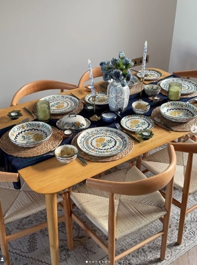 Scandi dining room with oak wood dining table, 6 wishbone chairs, pretty crockery in yellows and greens