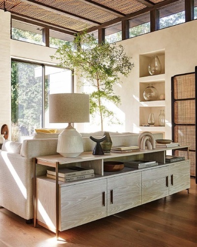low sideboard behind a sofa in a bright living space acts as room divider