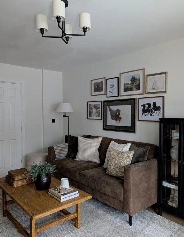 cosy small living room idea with white walls and dark furniture, with tan leather sofa, black storage cabinet and wood coffee table, and gallery wall