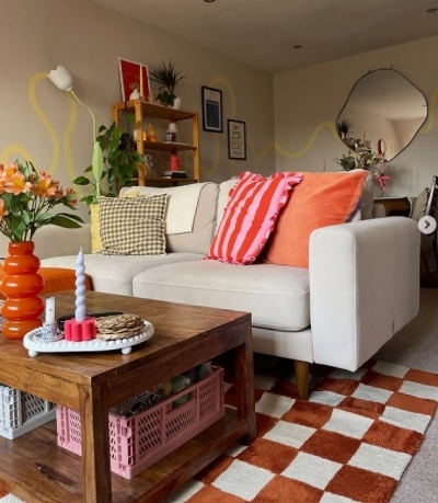 bold and colourful living room with sofa dressed in contrasting bold cushions in yellow, pink and stripes