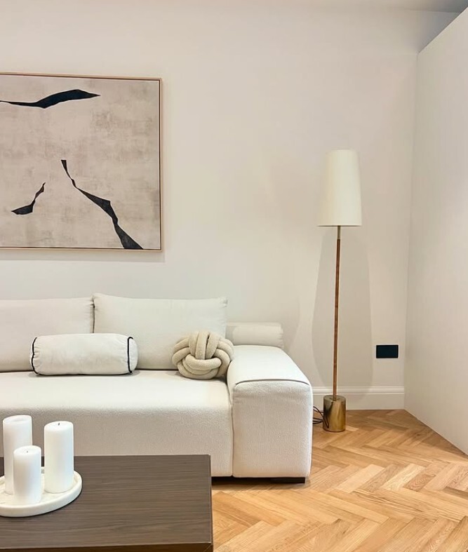 modern living room with cream fabric sofa, and standing lamp. Sofa is styled with structural cushions